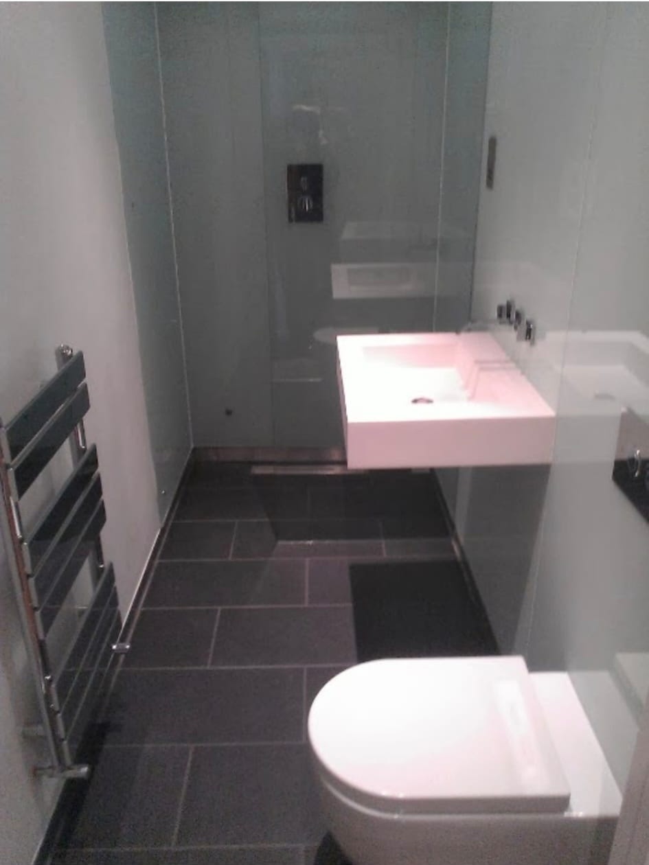 High-end wet room bathroom installation with dark floor tiles and floating basin.
