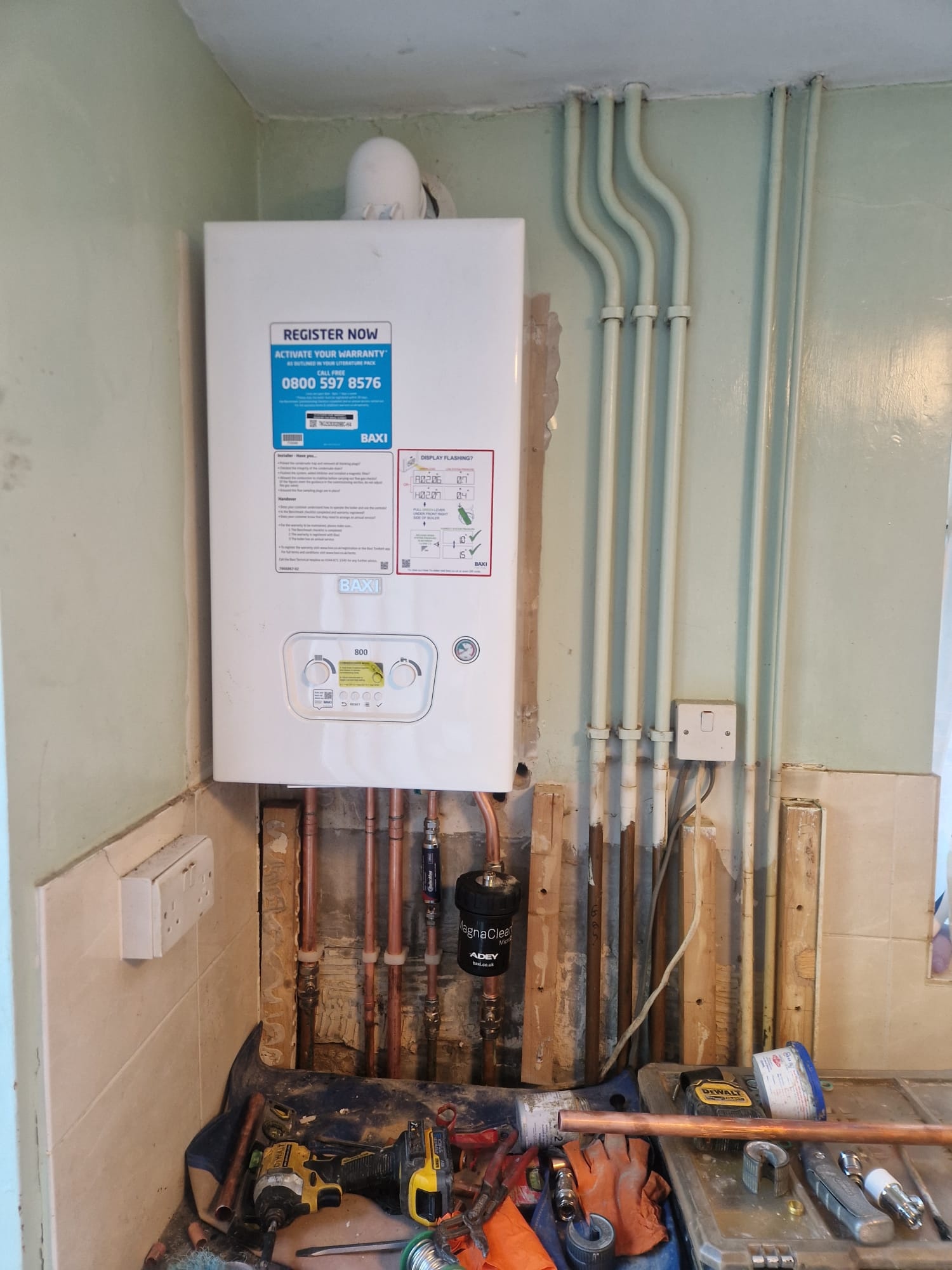 Baxi combi boiler installation on a kitchen wall with tidy copper pipework by DHP London.