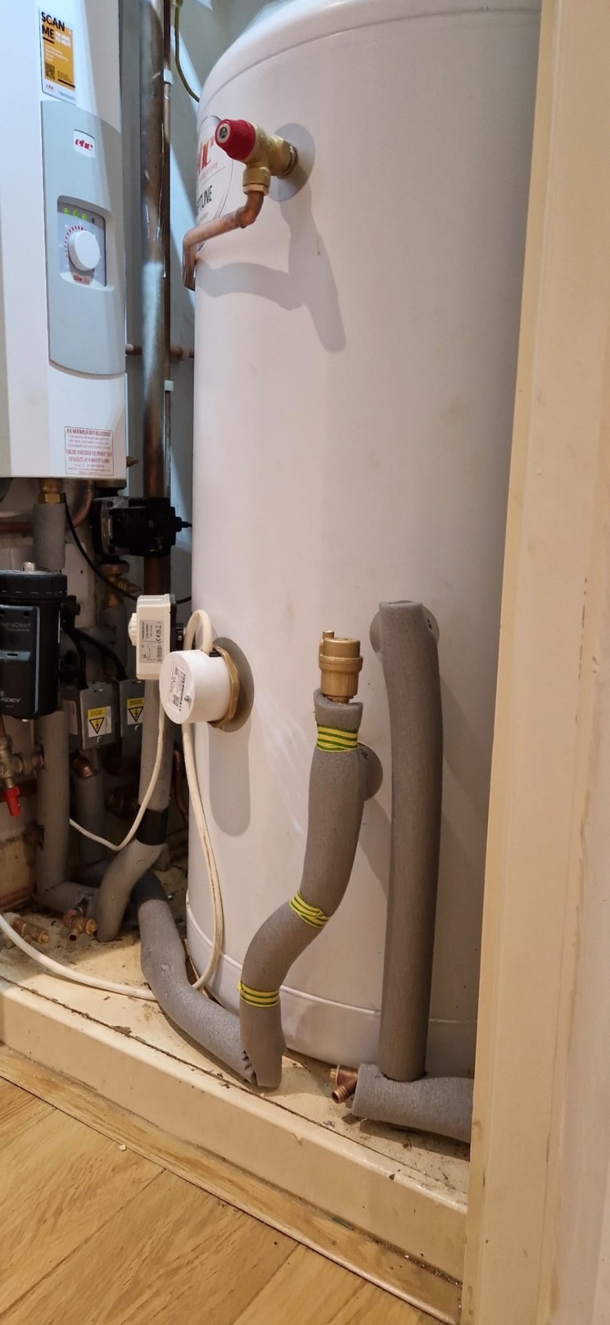 Insulated pipework detail at the base of a new unvented hot water cylinder.