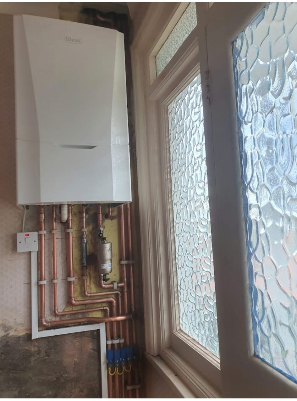 Ideal combi boiler mounted beside a patterned glass window in a London property.